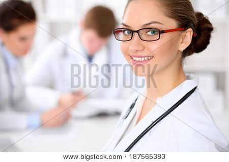Happy doctor woman  with medical staff at the hospital sitting at the table and discussing medical history
