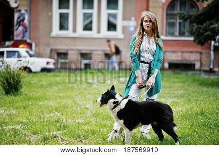 Trendy Girl At Glasses And Ripped Jeans With Russo-european Laika (husky) Dog On A Leash, Against St