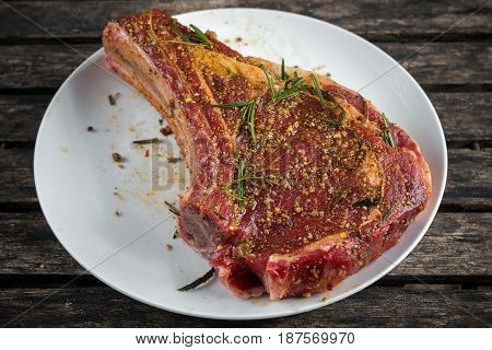 Fresh Raw Beef bone rib marinade with herbs on white plate