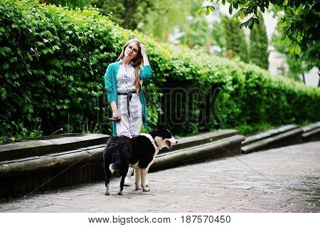 Trendy Girl At Glasses And Ripped Jeans With Russo-european Laika (husky) Dog On A Leash, Against St