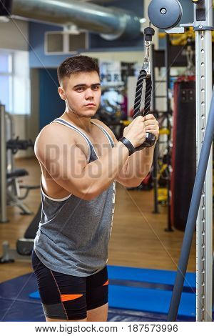 The guy is doing exercises on simulator in the gym.
