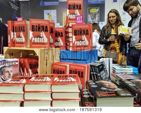 KIEV - UKRAINE - MAY 2017:  Art and book exhibition in Arsenal museum in Kiev. Table top made of pallets. Book named "War with Russia". On it rows and piles are books. Visitors inspects stuff.