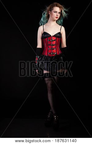 Sexy sensual woman in fetish red leather corset on black background in studio photo. BDSM and dominatrix