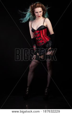 Beautiful woman in fetish red leather corset on black background in studio photo. BDSM and dominatrix
