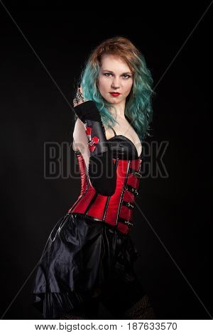 Slim woman in fetish red leather corset on black background in studio photo. BDSM and dominatrix