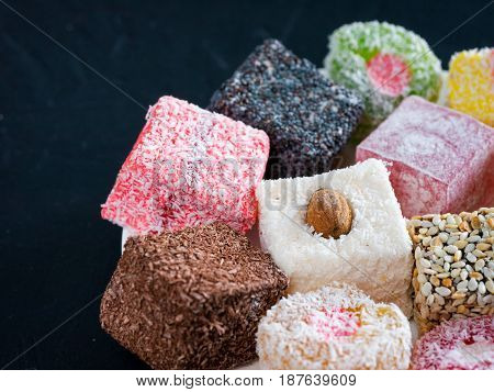 Turkish delight on black rustic background. Turkish deligh set. Assorted traditional turkish delight on oriental dark background