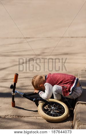 Photo of tired boy with bicycle in park