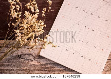 Top View And Warm Tone. White Bouquet Flower Putting Beside Calendar Page On Wooden Are Background.