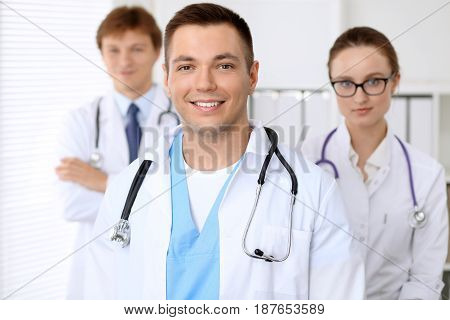 Cheerful smiling male doctor with medical staff at the hospital.
