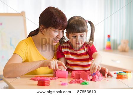 Child with therapist playing with toy the sand. Psychologist works sand therapy.