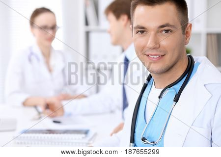 Cheerful smiling male doctor with medical staff at the hospital.