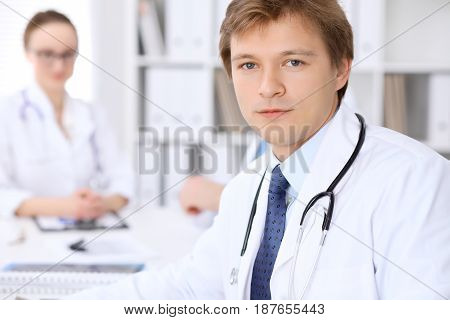 Cheerful smiling male doctor with medical staff at the hospital.