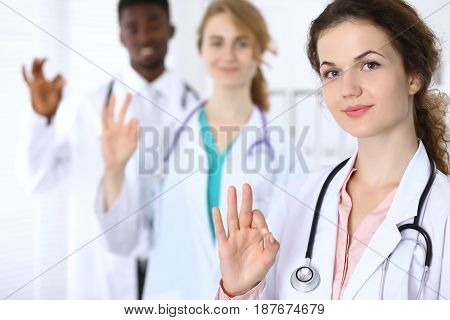 Happy doctor woman with medical staff at the hospital. Ok sign