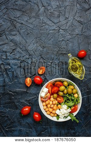 Spring vegetable salad with arugula cherry tomatoes chickpeas olives and feta cheese. Buddha bowl. Top view. Place for text.