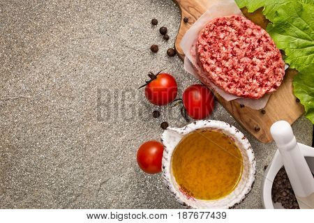 Raw beef meat steak cutlets with oil and spices on stone background top view with copy space