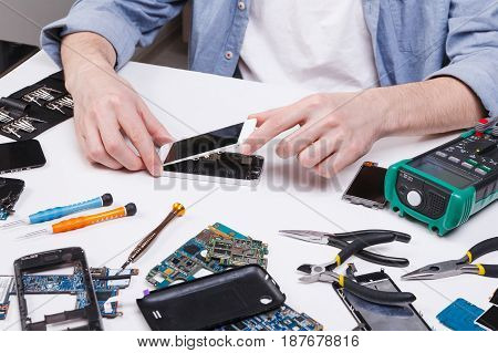 Repairman disassembling smartphone for inspecting. Technician fixing broken phone, electronics repair service