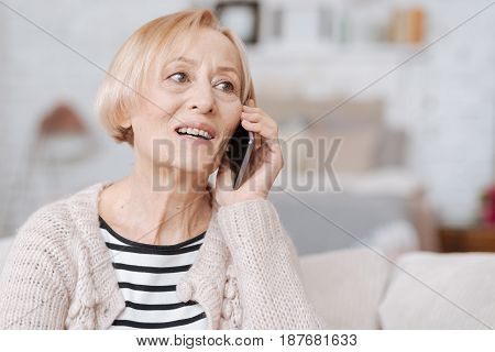 Hi there. Nice pleasant enthusiastic lady spending time at home and communicating with her acquaintance while sitting on a sofa in a living room