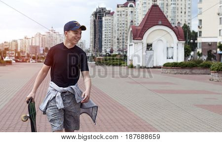 Young man with a skateboard on the street of a big city