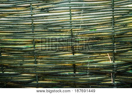 The texture of the translucent fence and the fence of wicker rods. Beach tents for changing clothes.