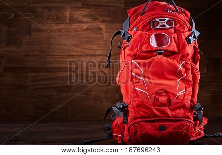 Close-up of the big hiking orange backpack against wooden background. Horizontal photo of the tourism rucksack. Tourism backgrounds and still-life. Preparation and planning for the travelling. Concept of the active lifestyle.