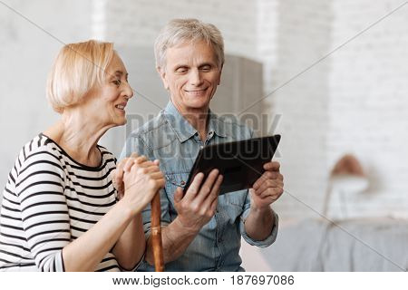 Engaging experience. Savvy intelligent senior gentleman using his gadget for demonstrating an interesting article he reading online