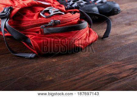 Hiking equipment: backpack and trekking boots on the wooden boards. Horizontal photo and brown background. Tourist backgrounds and still-life. Preparation and planning for the travelling. Concept of the active lifestyle.