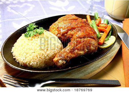 chicken leg with rice served on a hot sizzling plate