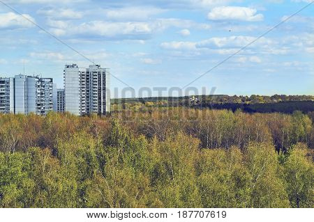 View of the high panel dwelling houses standing against a lonely church surrounded by dense forest