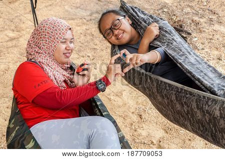 Labuan,Malaysia-Feb 19,2017:Young people relaxing & enjoying the hammock on tropical beach in Papan island,Labuan,Malaysia.