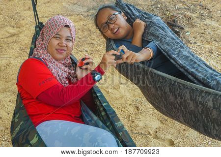 Labuan,Malaysia-Feb 19,2017:Young people relaxing & enjoying the hammock on tropical beach in Papan island,Labuan,Malaysia.