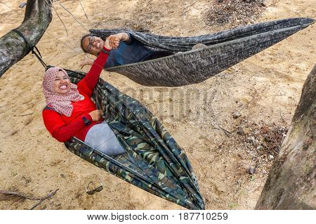 Labuan,Malaysia-Feb 19,2017:Young people relaxing & enjoying the hammock on tropical beach in Papan island,Labuan,Malaysia.
