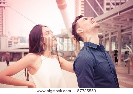 The girl is pulling the hair of a young man.