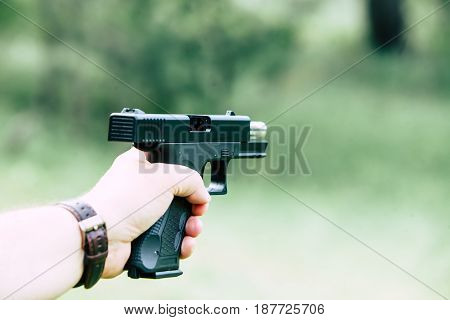 The gun is in his hand. The man is ready to shoot at the target