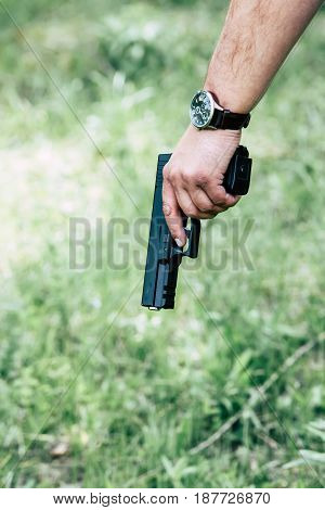 The gun is in his hand. The man is ready to shoot at the target