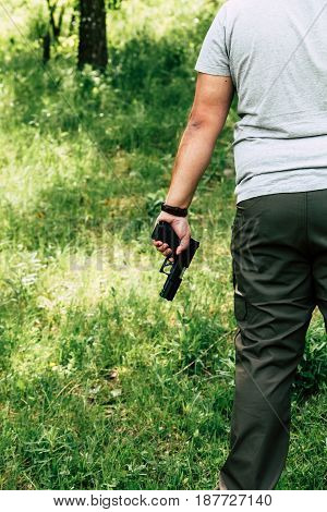 A man holds a bullet for a rifle and a pistol in his hand