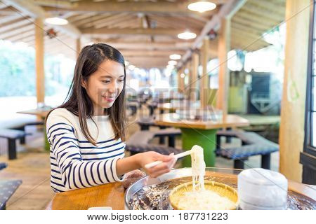 Woman having japanese water flow somen in restaurant