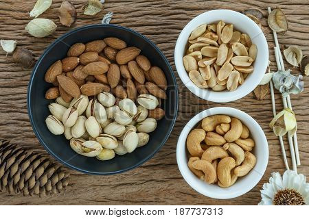 appetizer roasted delicious salt pistachios cashew nuts peanuts and almonds food in black bowl on wooden table background.