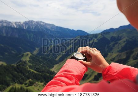 successful woman hiker checking the altimeter mountain top