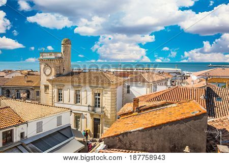  Yellow and orange tiled roofs and Mediterranean Sea. Morning gypsy carnival in a picturesque Provencal city Saintes-Maries-de-la-Mer. The concept of ethnographic tourism