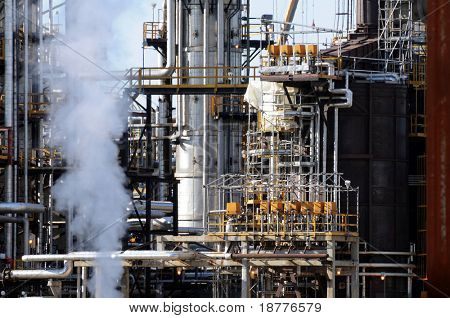 Closeup von Rauch steigt vor einer petrochemischen Anlage mit vielen Rohre