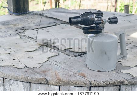 Blowtorch on wooden table background. Propane blowlamp.