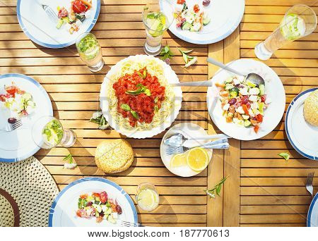 Family dinner variety of Italian dishes on wooden table in the garden top veiw