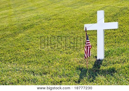 Closeup ein weißes Kreuz und eine amerikanische Flagge am Memorial Day gegen leichte grüne Gras mit copysp