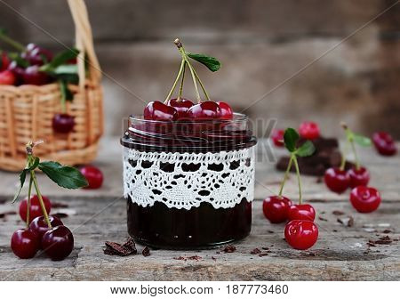 cherry jam with the chocolate in a glass jar and fresh cherries
