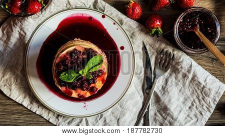 top view stack of homemade american pancakes served with jam and strawberries on wooden background.