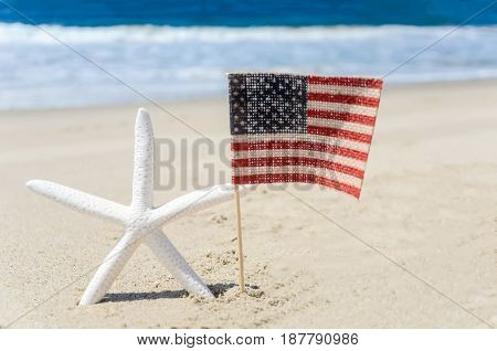 Patriotic USA background with starfish and american flag on the sandy beach