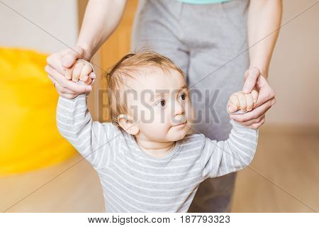 Cute boy taking first steps holding mums hands