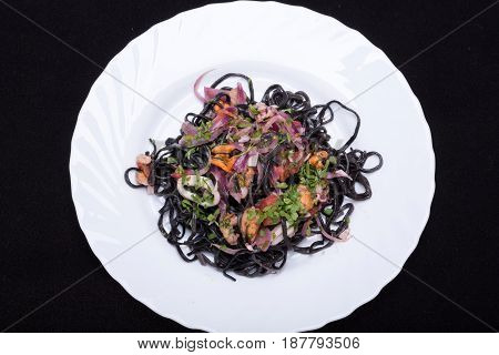 Black spaghetti with seafood and vegetables .