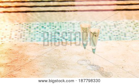Two Glasses Of Prosecco   At The Edge Of A Resort Pool. Concept Of Luxury Vacation