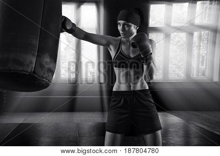 Fantastic sportswoman boxing in a gym with a bag